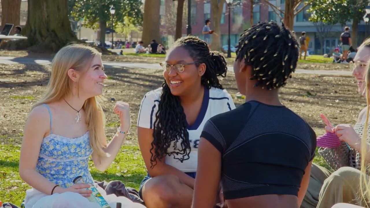 A diverse group of five students enjoying a beautiful sunny day while sitting down and chatting in VCU's Monroe Park 